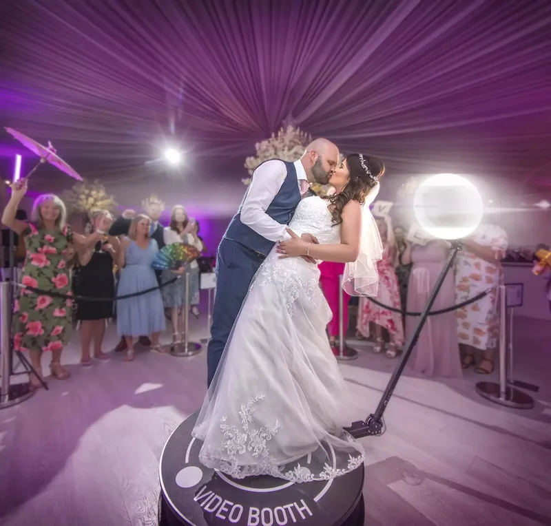 Newlyweds kissing on the 360° booth among their guests